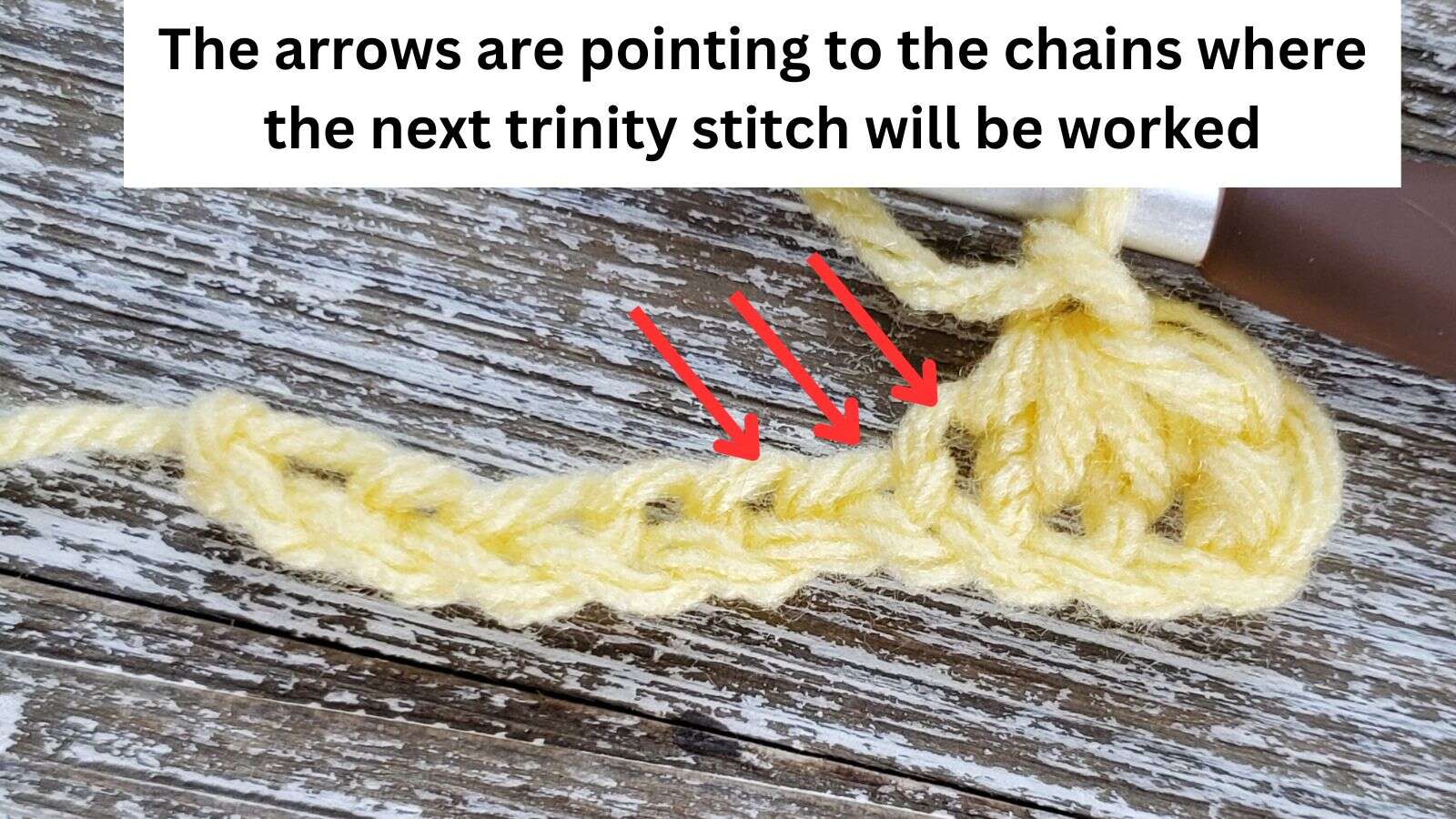 Arrows pointing to the chains where the next trinity stitch will be worked